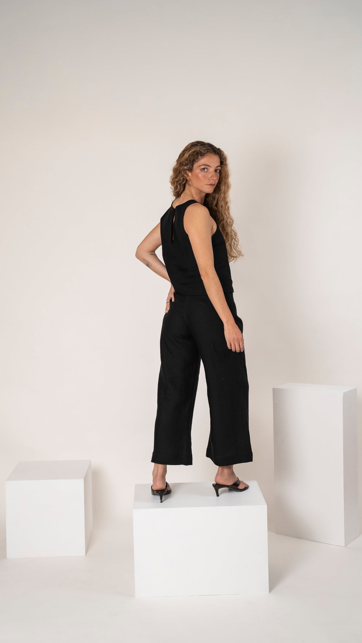 Pantalón de lino negro con pinzas, pierna ancha y corte relajado, con top de lino negro sin mangas, vista de frente