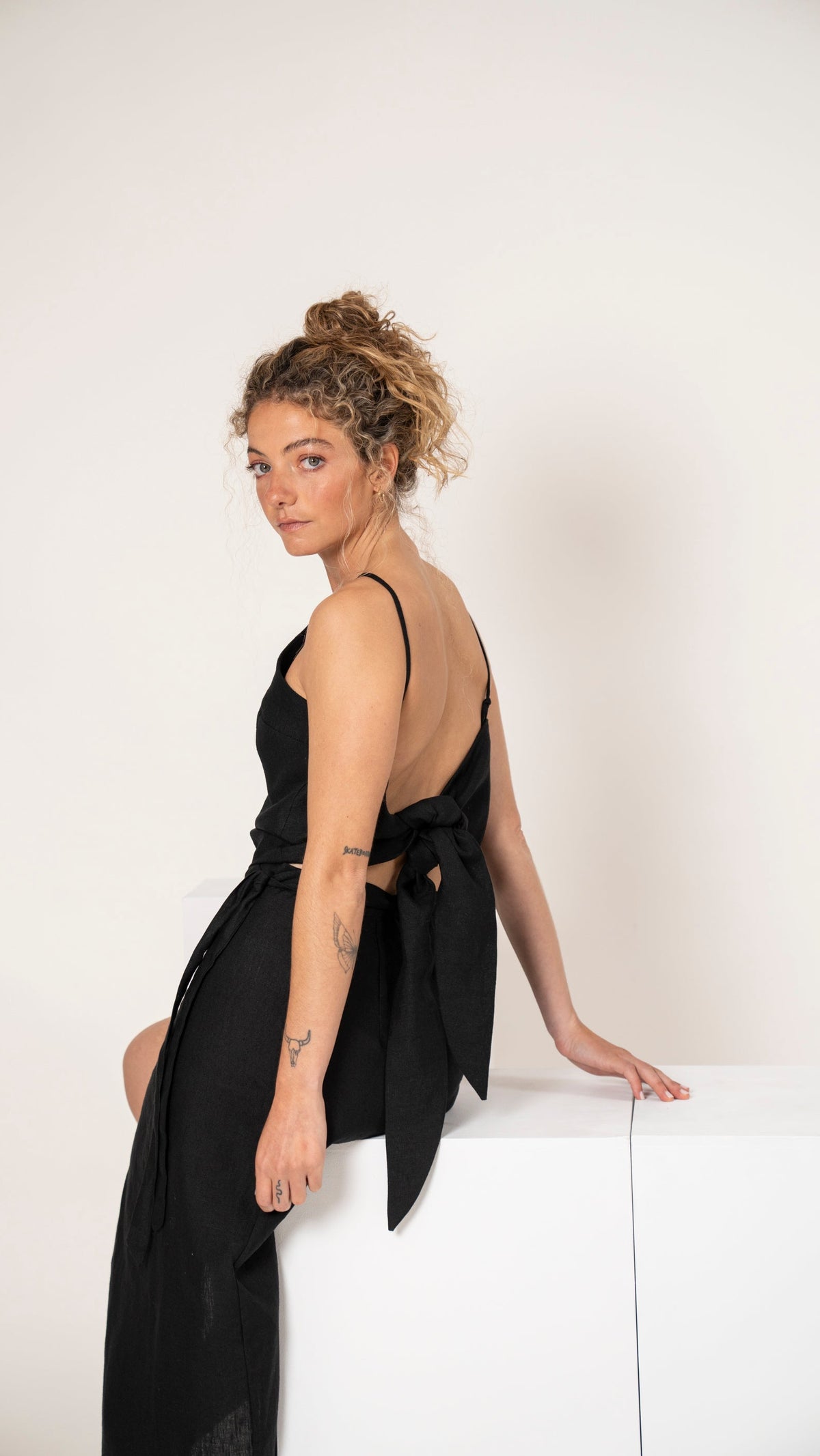 Polera de lino negra de tiritas con nudo y falda pareo negra con tajo, vista de perfil
