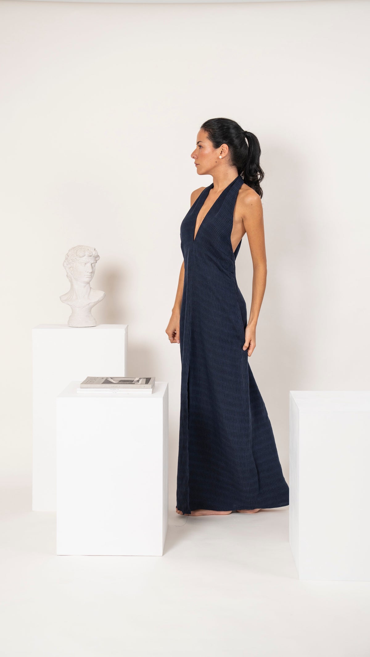 Vestido largo de lino azul con escote en V profundo y silueta alargada, vista de tres cuartos