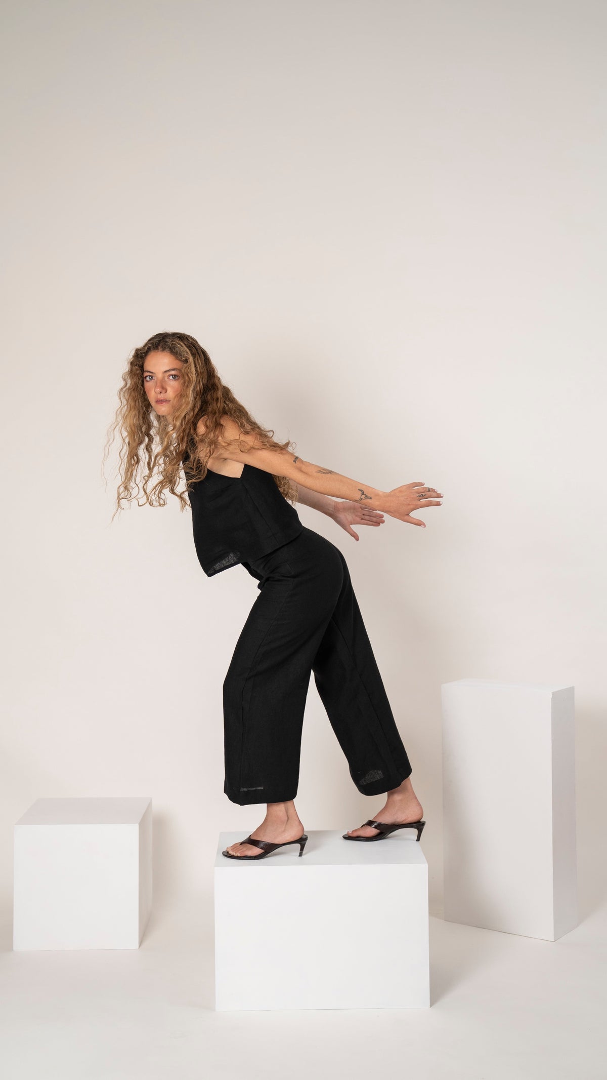 Pantalón de lino negro con pinzas y pierna ancha, se ve la caída del lino en movimiento